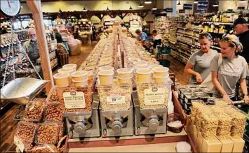  ?? Photos by Lori Van Buren / Times Union ?? Customers shop in the bulk section of the Saratoga Springs Fresh Market grocery store. Loyal customers can save in both this and at the Latham location.