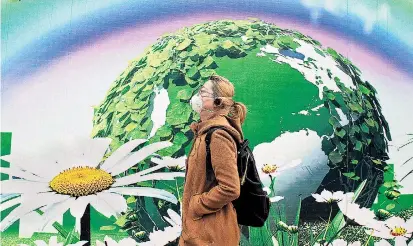  ??  ?? Eine Passantin mit Atemmaske im versmogten Peking vor einem Plakat, das eine heilere Umwelt zu verspreche­n scheint. Die chinesisch­e Regierung verspürt Druck, die Luftqualit­ät zu verbessern.