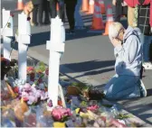  ?? DAVID ZALUBOWSKI/AP ?? Dallas Dutka, whose cousin was killed in the Club Q shooting, prays Tuesday by a makeshift memorial for the victims in Colorado Springs, Colorado.