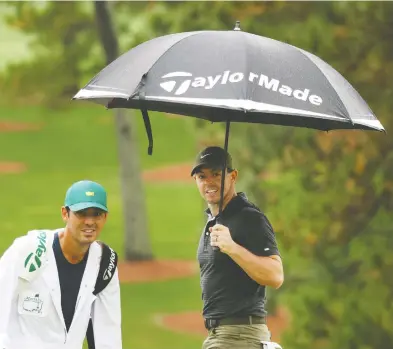  ?? ROB CARR / GETTY IMAGES ?? Rory McIlroy of Northern Ireland takes cover under an umbrella with caddie Harry Diamond during a practice
round prior to the Masters at Augusta National Golf Club on Wednesday.