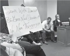  ?? Staff photo by Lynn Larowe ?? ■ A resident holds up a poster before a special City Council meeting Thursday in New Boston, Texas. The meeting was held to address whether City Secretary Darla Faulknor should be terminated for lack of confidence. Faulknor, in the background wearing...