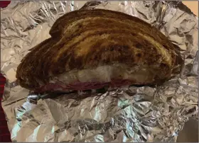  ?? (Arkansas Democrat-Gazette/Eric E. Harrison) ?? For takeout, the kitchen at EJ’s Eats & Drinks wraps each half of the reuben separately in aluminum foil.