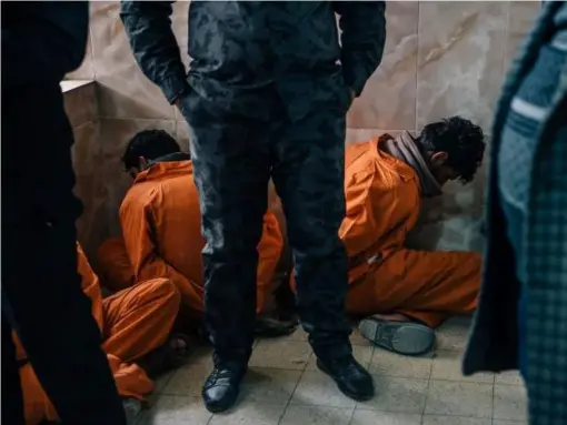  ??  ?? Prisoners sit with their hands tied behind their backs inside the appeals court in Ramadi