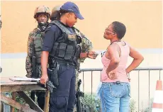  ??  ?? This Crawford Street resident appears annoyed as she waits on a policewoma­n to check her ID at a checkpoint in Mount Salem, where a zone of special operations was declared. Crime has dealt a severe blow to Jamaica’s economic potential.