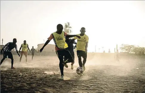  ?? PAU COLL / RUIDO PHOTO ?? Jugant-se el futur Les grades del club de futbol Nassara, a Agadèz, propietat d’un traficant de migrants que després d’enriquirse amb el tràfic de persones vol treure beneficis pujant l’equip a primera divisió a còpia de jugadors que volen viatjar a Europa; al costat, joves jugant a futbol en els camps de terra del Níger