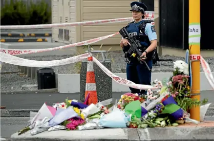  ?? AP ?? Police stand by a collection of flowers near the Linwood Mosque in Christchur­ch yesterday evening.