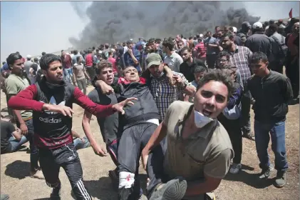  ?? AP PHOTO ?? Palestinia­n protesters carry an injured man who was shot by Israeli troops during a deadly protest at the Gaza Strip’s border with Israel, east of Khan Younis, Gaza Strip, Monday.