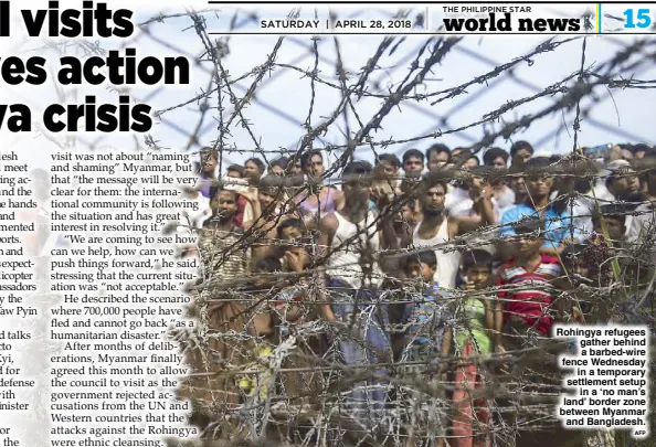  ?? AFP ?? Rohingya refugees gather behind a barbed-wire fence Wednesday in a temporary settlement setup in a ‘no man’s land’ border zone between Myanmar and Bangladesh.