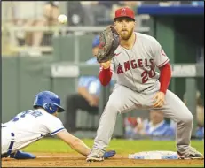  ?? Associated Press ?? The Royals’ Andrew Benintendi (left) dives safely back to first base on a pickoff-attempt to Angels first baseman Jared Walsh (20) during the first inning, Monday, in Kansas City, Mo.