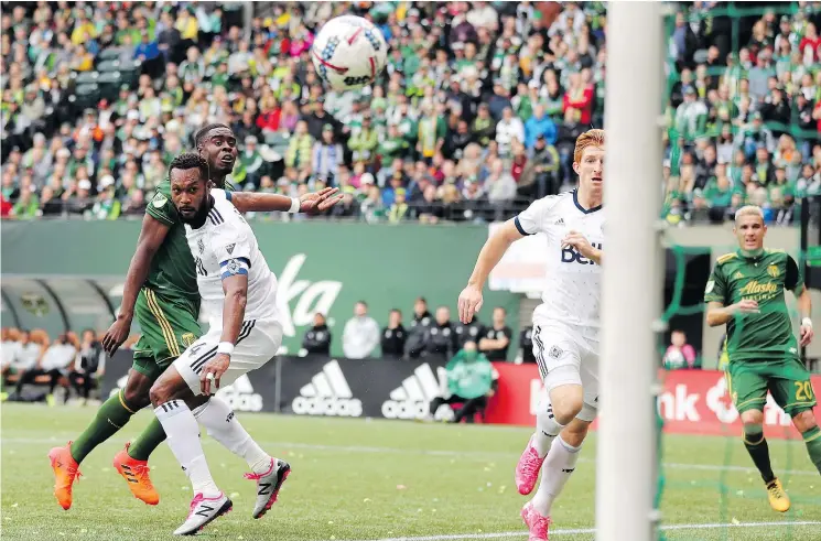  ?? — USA TODAY SPORTS ?? The Whitecaps’ Kendall Waston, front left, watches the ball go in after heading it over the Timbers’ Larrys Mabiala, rear left, for a goal at Providence Park.