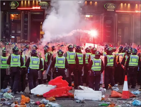  ??  ?? Flares fly as Rangers fans in Glasgow city centre are moved back by police officers carrying riot shields