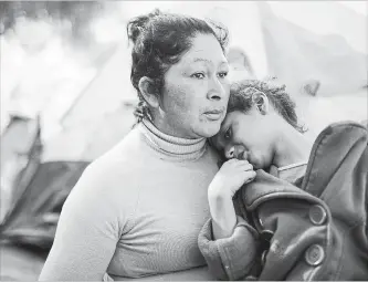  ?? MARIO TAMA GETTY IMAGES ?? Honduran migrants sit in a temporary shelter on Monday that was set up for members of their caravan in Tijuana, Mexico. About 6,000 migrants from Central America have arrived in the border city with the U.S.