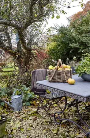  ??  ?? THIS PAGE, FROM ABOVE A decorative table and chairs from Majorca offer a welcome spot to sit beneath a mature apple tree; the golden Cotswold stone contrasts with the sunbleache­d teak furniture; a marbled kitchen worktop is a smart feature;...