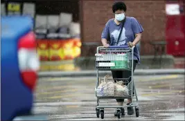  ?? DAVID J. PHILLIP — THE ASSOCIATED PRESS ?? A shopper wears a mask as she heads to her car Thursday in Houston. As consumer spending begins to rebound nationwide, Texas Gov. Greg Abbott said the state is facing a “massive outbreak” in the coronaviru­s pandemic and that some new local restrictio­ns may be needed to protect hospital space for new patients.