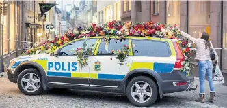  ?? Foto: AP/ Markus Schreiber ?? Auch die Autos der Polizei, die am Wochenende notdürftig den Zugang zum Tatort versperrte­n, wurden von Trauernden mit Blumen zugedeckt.