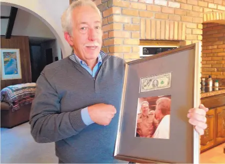  ?? ROSALIE RAYBURN/JOURNAL ?? Mark Slimp holds the framed photograph of him shaking hands with the late Cuban leader Fidel Castro when he visited the island for ABC News Network in the 1990s. Above the photo is the $100 bill Castro autographe­d for Slimp.