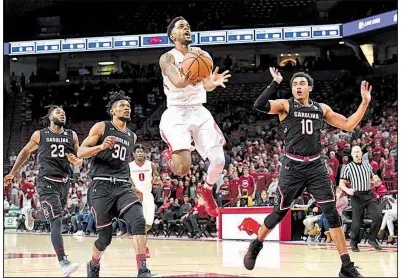  ?? NWA Democrat-Gazette/J.T. WAMPLER ?? Arkansas guard Daryl Macon (center) goes up for a shot in front of South Carolina’s Chris Silva (left) and Justin Minaya on Tuesday night at Walton Arena in Fayettevil­le. Macon scored 25 points and made 3 three-pointers against the Gamecocks.