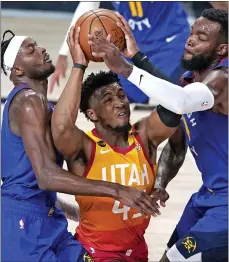  ?? ASSOCIATED PRESS FILE PHOTO ?? Utah Jazz’s Donovan Mitchell, center, goes up to shoot as Denver Nuggets’ Jerami Grant, left, and Paul Millsap, right, defend during the second half of a 2020 first round playoff game in Lake Buena Vista, Fla.