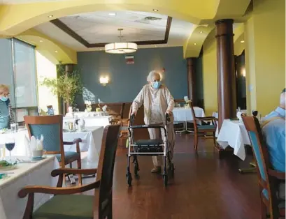  ?? SETH WENIG/AP ?? May Nast arrives for dinner at RiverWalk, an independen­t senior housing facility in New York, on April 1, 2021. COVID-19 infections are soaring again at U.S. nursing homes because of the omicron wave, and deaths are climbing too. That’s leading to new restrictio­ns on family visits and a renewed push to get more residents and staff members vaccinated and boosted.