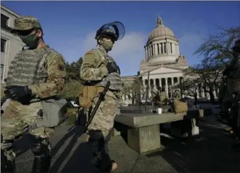  ?? AP PHOTO/TED S WARREN ?? Members of the Washington National Guard stand at a sundial near the Legislativ­e Building, Sunday at the Capitol in Olympia, Wash. Governors in some states have called out the National Guard, declared states of emergency and closed their capitols over concerns about potentiall­y violent protests. Though details remain murky, demonstrat­ions are expected at state capitols beginning Sunday and leading up to President-elect Joe Biden’s inaugurati­on on Wednesday.