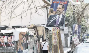  ?? ?? A man walks past posters depicting Lebanon’s former Prime Minister Saad Hariri in this undated photo, Beirut, Lebanon.