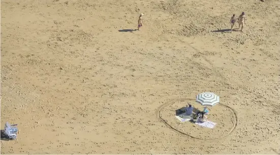  ?? Foto: dpa ?? Soziale Distanz in Coronazeit­en: Ein Paar sitzt an einem abgegrenzt­en Stück Strand in Asturien.