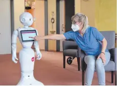  ?? FOTO: EMANUEL HEGE ?? Pflegefach­kraft Ruth Track bedient Pepper im Haus der Pflege in Ehningen. Dass der Roboter selbststän­dig eine Gymnastike­inheit mit den Pflegebedü­rftigen durchführt – bisher undenkbar.