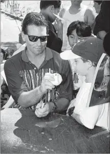  ?? Tara Farrell Associated Press ?? TOM CANDIOTTI, whose fan club was called the Knucklehea­ds, shows a young admirer how to throw the pitch in 1994.