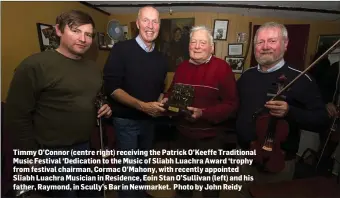  ??  ?? Timmy O’Connor (centre right) receiving the Patrick O’Keeffe Traditiona­l Music Festival ‘Dedication to the Music of Sliabh Luachra Award ‘trophy from festival chairman, Cormac O’Mahony, with recently appointed Sliabh Luachra Musician in Residence, Eoin Stan O’Sullivan (left) and his father, Raymond, in Scully’s Bar in Newmarket. Photo by John Reidy