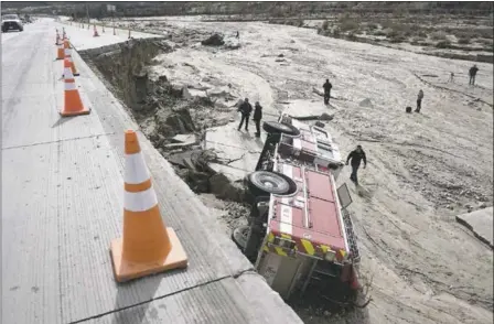  ?? DAVID PARDO/THE DAILY PRESS VIA THE ASSOCIATED PRESS FILE ?? Officials look over the scene at Interstate 15in the Cajon Pass, Calif., where part of the freeway collapsed from, heavy rain, bring down a San Bernardino County firetruck and a big rig in February.