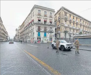  ?? REUTERS ?? Italian soldiers wearing protective masks work at a roadblock after Italy reinforced the lockdown measures to combat the coronaviru­s n disease in Catania.