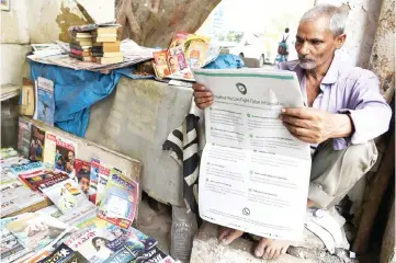  ?? — AFP photo ?? An Indian newspaper vendor reading a newspaper with a full back page advertisem­ent fromWhatsA­pp intended to counter fake informatio­n, in New Delhi.