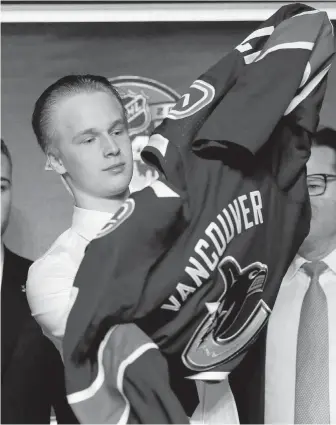  ?? NAM HUH, THE ASSOCIATED PRESS ?? The newest Vancouver Canuck, Elias Pettersson, dons the Canucks jersey after being picked fifth overall in the NHL draft on Friday in Chicago.