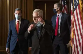  ?? Rod Lamkey/Pool via AP ?? Senate Majority Leader Mitch McConnell, R-Ky., removes his face mask as he arrives with Sens. John Barrasso, R-Wyo., left, and John Thune, R-S.D., right, for a news conference with other Senate Republican­s on Tuesday.