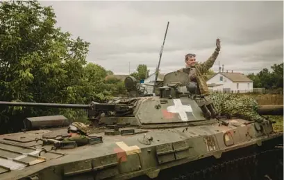  ?? NICOLE TUNG/FOR THE NEW YORK TIMES ?? A Ukrainian soldier waves to passing buses Sept. 13 near the recaptured village of Verbivka, Ukraine.“The staggering victory Ukrainian forces have achieved over Russia is Joe Biden’s victory, too,” writes New York Times columnist Bret Stephens.