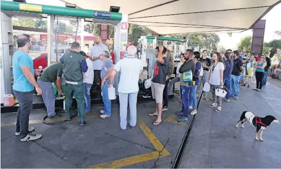  ?? ANDRE DUSEK/ESTADÃO ?? Desabastec­imento. Dezenas de pessoas fazem fila para comprar gasolina com galão no posto próximo à Universida­de de Brasília, na capital federal