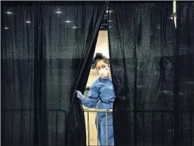  ?? [JOHN LOCHER/ THE ASSOCIATED PRESS] ?? Diana Vega, a registered respirator­y therapist, peeks through a curtain during setup at a temporary coronaviru­s testing site Monday in Las Vegas.