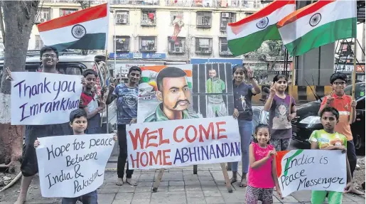  ?? PHOTO: REUTERS ?? Welcome news: Children hold banners and flags on a street in Mumbai after Pakistan said it would release an Indian air force pilot today.