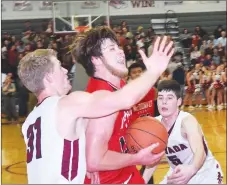  ?? RICK PECK/SPECIAL TO MCDONALD COUNTY PRESS ?? McDonald County’s Cooper Reece gets past Nevada’s Dalton Gayman (31) and Logan McNeley (5) to score two of his game-high 26 points in the Mustangs’ 62-52 loss to Nevada on Feb. 8 at Nevada High School.