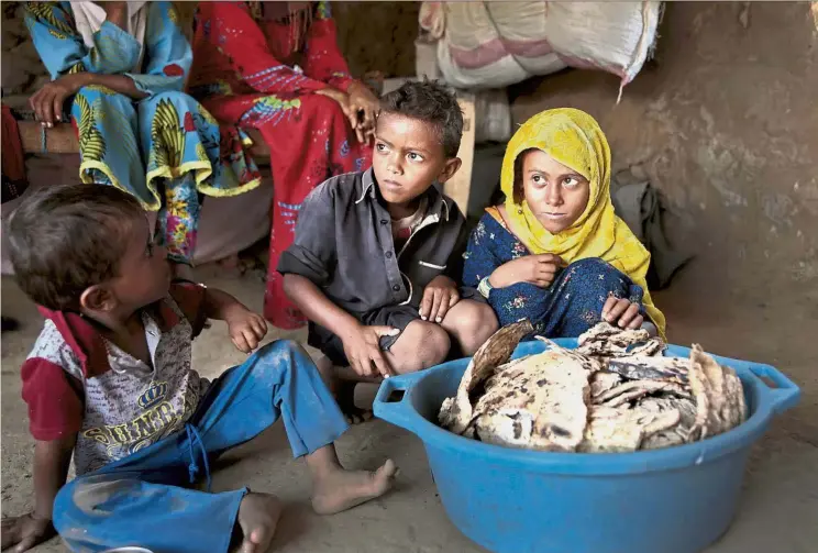  ?? — Photos: AP ?? Just surviving: Children waiting to eat the bread made from mouldy hard bread crumbs mixed with water and salt.