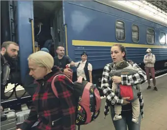 ?? Carolyn Cole Los Angeles Times ?? PASSENGERS arrive at the station in Lviv after a 22-hour train journey from Dnipro, Ukraine. Having left behind the horrors of the Russian invasion in their cities, some were anxious but also relieved.