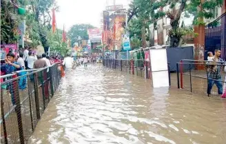  ??  ?? Devotees face inconvenie­nce due to flooding at the Khairataba­d Ganesh pandal due to the downpour on Monday evening.