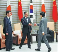  ?? KIM KYUNG-HOON / REUTERS ?? Japanese Prime Minister Shinzo Abe (right) greets Chinese Foreign Minister Wang Yi (center) and Republic of Korea Foreign Minister Yun Byung-se at their meeting in Tokyo on Wednesday.