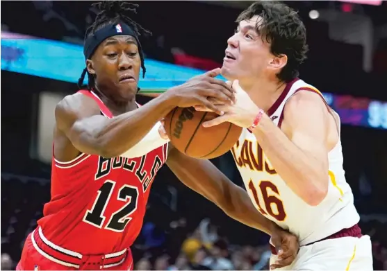  ?? TONY DEJAK/AP ?? Bulls rookie guard Ayo Dosunmu, who had nine points and shot 4-for-7 from the field, ties up Cavaliers forward Cedi Osman on Sunday night.