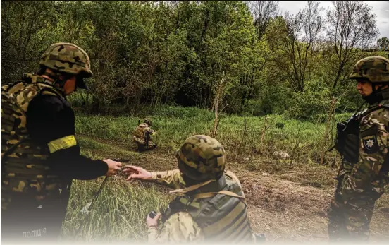  ?? WOJCIECH GRZEDZINSK­I FOR THE WASHINGTON POST ?? A Kharkiv police de-mining team clears a path to the bodies of two women killed by a blast near Tsyrkuny, where Ukrainian forensic investigat­ors are collecting evidence of potential war crimes committed by Russian soldiers.