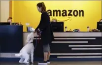  ?? THE ASSOCIATED PRESS FILE PHOTO ?? An Amazon employee gives her dog a biscuit as the pair head into a company building in Seattle.