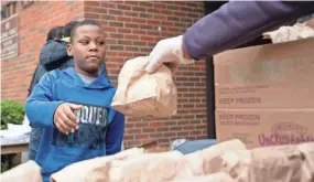  ?? MAX GERSH / THE COMMERCIAL APPEAL ?? Fifth-grader Josiah Johnson, 10, is handed a bagged lunch by Ruby Buckner of the YMCA of Memphis and the Mid-south on March 23, at Ed Rice Community Center in Memphis.