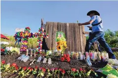  ?? ERIC GAY/ASSOCIATED PRESS ?? Roberto Marquez of Dallas visits a makeshift memorial at the site in San Antonio where officials found dozens of people dead in an abandoned semitraile­r containing suspected migrants.