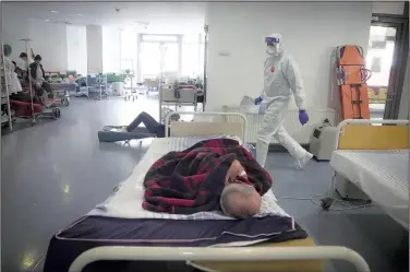  ?? ?? Seen through a plastic sheet, a member of the medical staff checks on covid-19-positive patients Monday at the University Emergency Hospital waiting area, converted into a covid-19 section due to the number of cases in Bucharest.