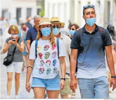  ?? JAVIER ALBIÑANA ?? Gente pasea con mascarilla­s en las calles de Málaga.